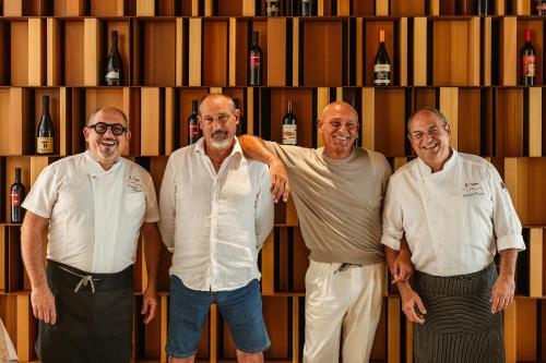 four men standing in front of a shelf with wine bottles at Hotel Tannure in San Vito lo Capo