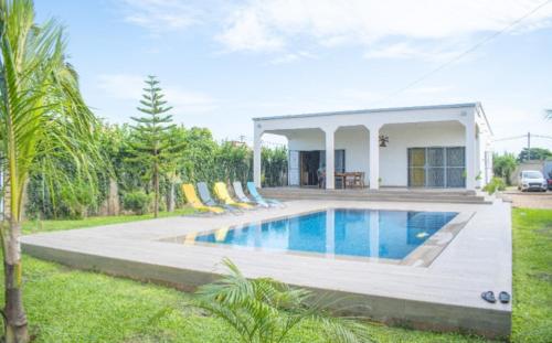 a house with a swimming pool with chairs around it at Elysee in Mbour