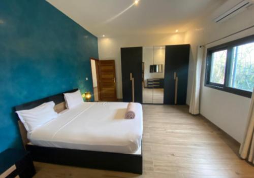 a bedroom with a white bed and a blue wall at Elysee in Mbour