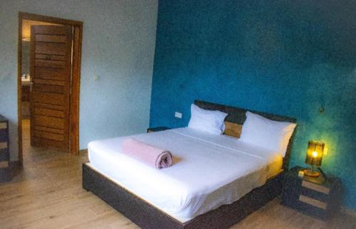 a bedroom with a large white bed with a blue wall at Elysee in Mbour