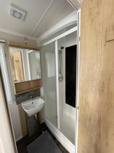 a small bathroom with a sink and a shower at Luxury Family Caravan With Decking and Sea View - Sleeps 6 in Allhallows