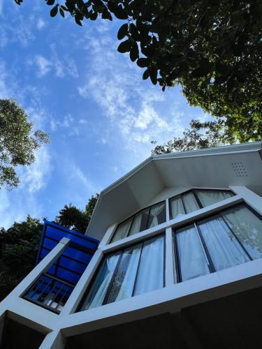 a white house with a blue window and trees at Sunset Island View Villa El Nido in El Nido