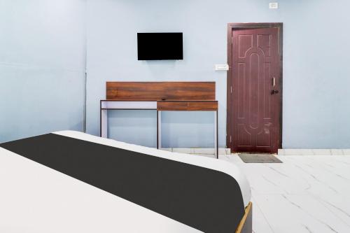 a bedroom with a bed and a tv and a door at Hotel O Dharohar in Rishīkesh