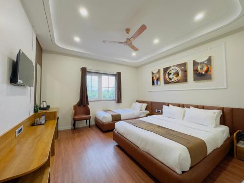 a hotel room with two beds and a television at Hotel Royale Heritage in Ujjain