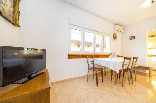 a dining room with a table with chairs and a television at Apartments Borik in Zadar