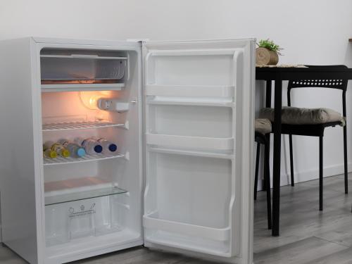 a white refrigerator with its door open next to a table at Souto 25 - T0 na Régua in Peso da Régua