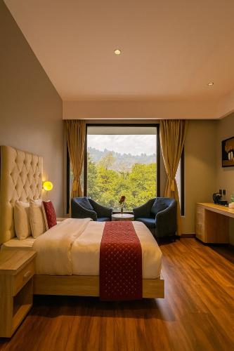 a bedroom with a large bed and a large window at The Maple Woods Resort in Rāmnagar
