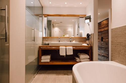a bathroom with a tub and a sink and a mirror at Europe Hotel & Spa in Zermatt