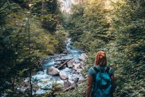 a woman with a backpack walking down a river at Bella Vista Ferienwohnung in Bürs