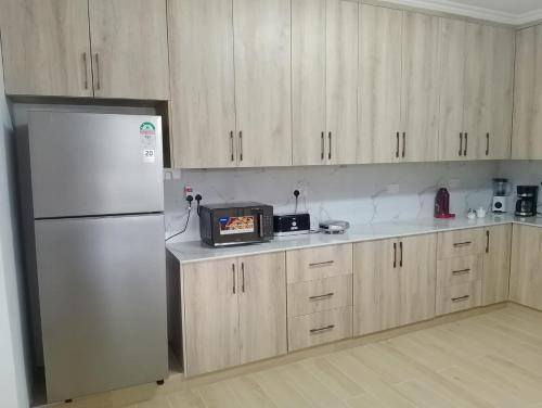 a kitchen with a stainless steel refrigerator and wooden cabinets at Mysore House - Nanyuki in Nanyuki