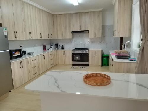 a kitchen with wooden cabinets and a white counter top at Mysore House - Nanyuki in Nanyuki