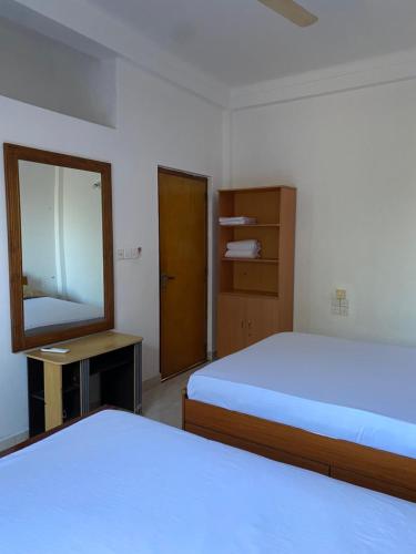 1 Schlafzimmer mit 2 Betten, einem Spiegel und einer Tür in der Unterkunft Eesan Guest House in Trincomalee