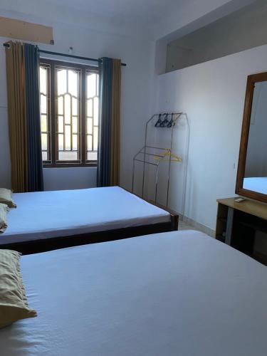 1 Schlafzimmer mit 2 Betten, einem Spiegel und einem Fenster in der Unterkunft Eesan Guest House in Trincomalee