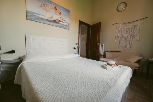 a bedroom with a white bed and a chair at Palazzetto del Pittore in San Quirico d'Orcia in San Quirico dʼOrcia