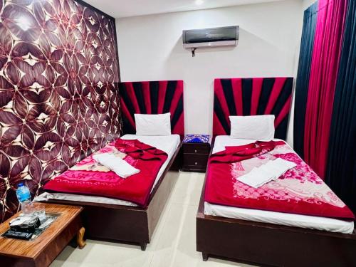 two beds in a room with red sheets at Sweet Villa Guest House Islamabad in Islamabad