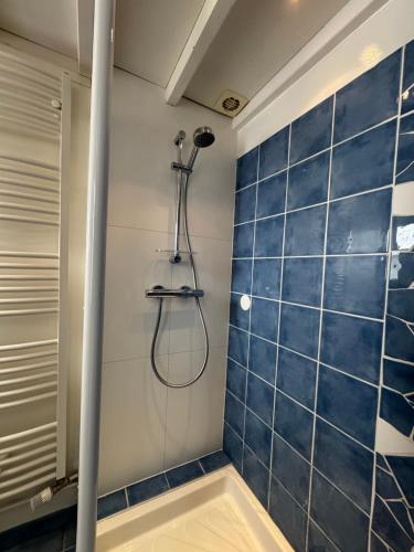 eine Dusche im Bad mit einer blau gefliesten Wand in der Unterkunft Riquette in Le Touquet-Paris-Plage