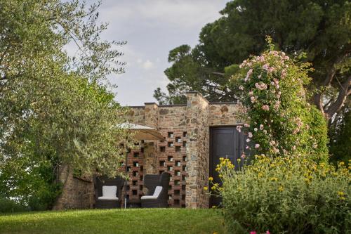 a brick house with two chairs in a yard at Poggio Piglia in Chiusi