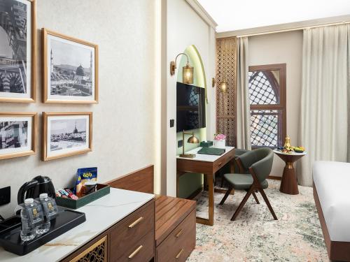 a hotel room with a desk and a bedroom at Elaf Taiba Hotel in Al Madinah