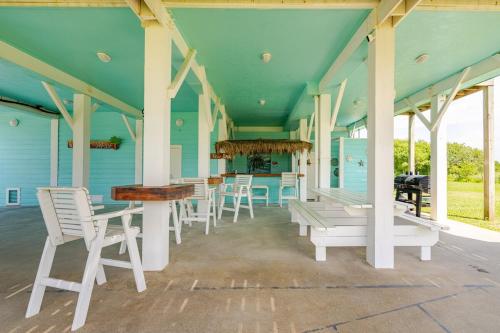 Un porche con sillas y mesas blancas en una casa azul. en Views, 3 King Suites, 15 Guests, en Bolivar Peninsula