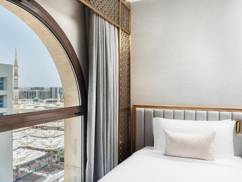 a bedroom with a bed and a large window at Elaf Taiba Hotel in Al Madinah