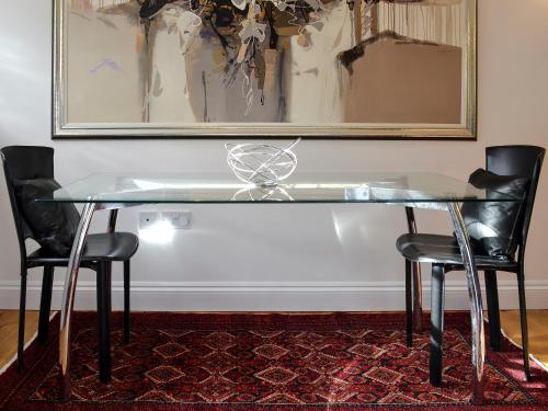 a glass table with two chairs and a picture on the wall at The Old Rectory Lodge in Yaxham