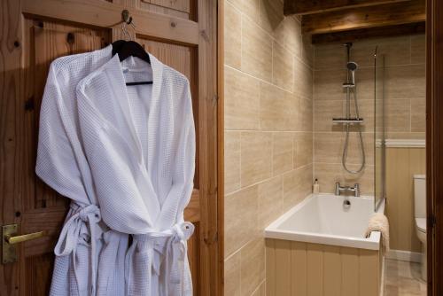 a white robe hanging on a door in a bathroom at The Bothy, Press Mains Farm Cottages in Eyemouth