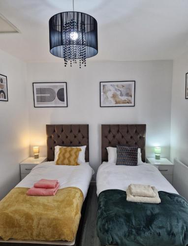 a bedroom with two beds and a chandelier at Ampee Guest Suite-Free Parking in Liverpool