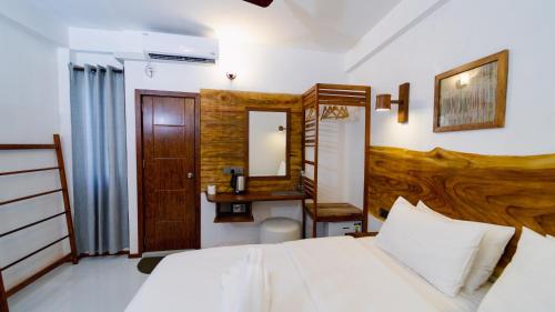 a bedroom with a bed and a desk and a mirror at Turtle Hive - Velaa Vani in Dhiffushi