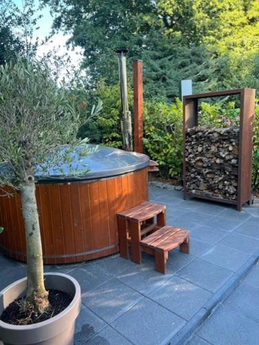a hot tub and a bench next to a tree at Kip en Hei in Schijf