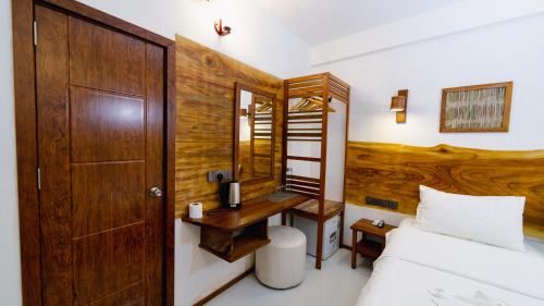 a bedroom with a bed and a wooden headboard at Turtle Hive - Velaa Vani in Dhiffushi