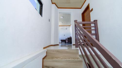 a staircase in a house with white walls and a window at Turtle Hive - Velaa Vani in Dhiffushi