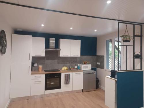 a kitchen with white cabinets and a blue wall at Maison de campagne à Château-Chervix in Château-Chervix