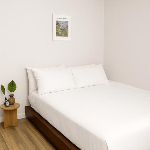 a white bed in a white bedroom with a table at 스카이스테이 in Daejeon