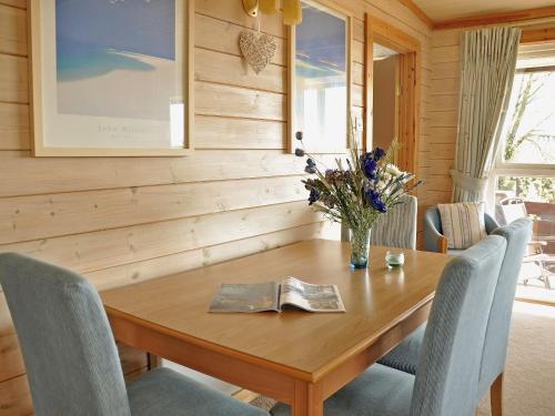 a wooden table with chairs and a vase of flowers on it at Hawthorne in Woolfardisworthy