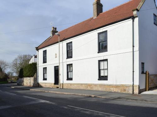 a white building with a red roof on a street at West House Farm in Filey