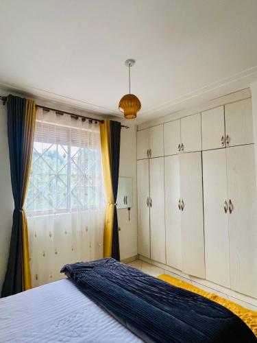 un dormitorio con una cama y una ventana en Ruth Flora Apartment, en Kampala