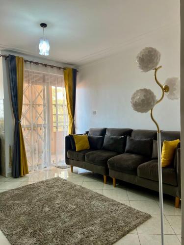 a living room with a black couch and yellow pillows at Ruth Flora Apartment in Kampala