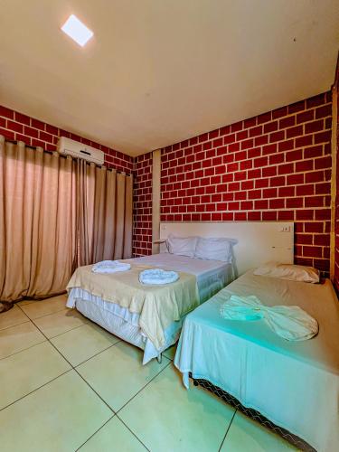 two beds in a room with a brick wall at POUSADA MARTINS in Carolina