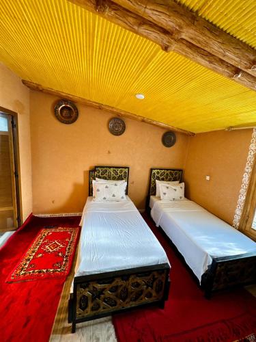 two beds in a room with a yellow ceiling at Villa Mouloud, arougou khenifra in Arrougou