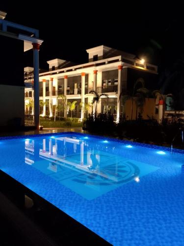 a swimming pool in front of a building at night at Rajbari Resort in Shānti Niketan