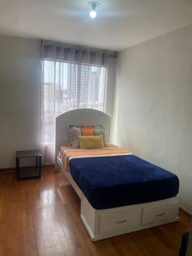 a bedroom with a bed with a blue comforter and a window at Miraflores Moonlight in Lima