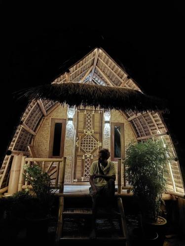 een man die voor een huis zit bij The Twins Sunset Bungalow in Palebah