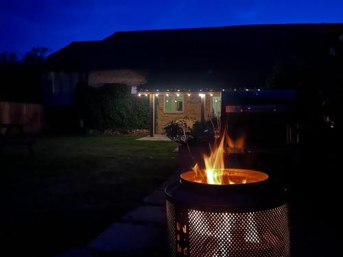 a fire pit in front of a house at night at Private & Spacious Cotswold Barn in Hankerton