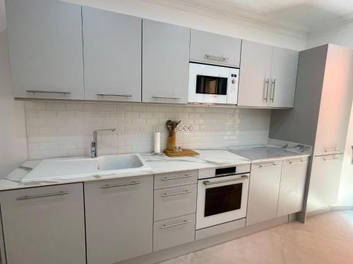 a white kitchen with white cabinets and a sink at Appartement T3 Place du Marché in Bastia