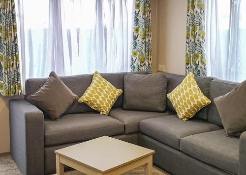 a living room with a gray couch with yellow pillows at Stanwix Park in Silloth