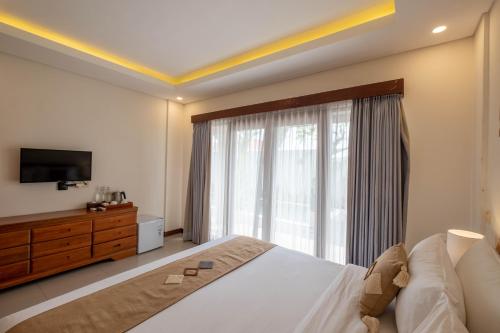 a bedroom with a bed and a tv and a window at Kubu Belona Canggu in Canggu
