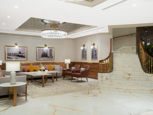 a lobby with couches and tables and a staircase at Elaf Taiba Hotel in Al Madinah