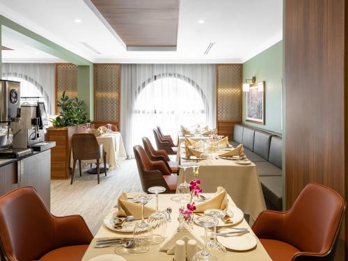 a restaurant with long tables and chairs and a kitchen at Elaf Taiba Hotel in Al Madinah
