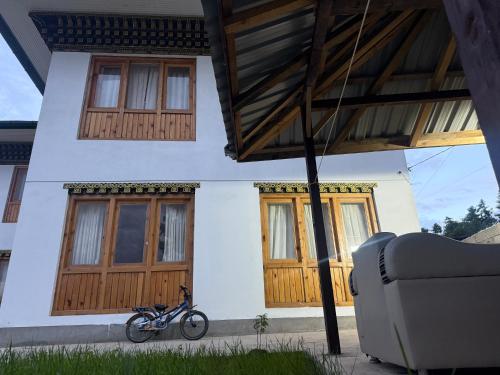 Una bicicleta estacionada frente a una casa con puertas de madera. en Sompal Serviced Apartment, en Paro