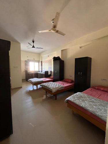 a room with three beds and a ceiling fan at Home Nest PG in Anand